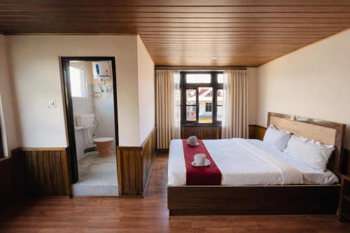 a bedroom with a large bed and a bathroom at Hotel Tashiling Stay in Pelling