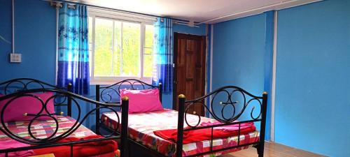 two beds in a room with blue walls and a window at Krasom Homestay in Phang-nga