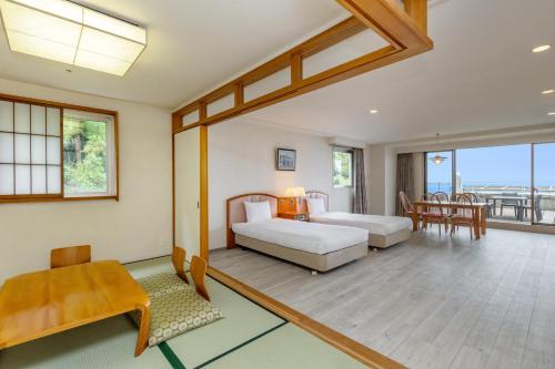 a bedroom with two beds and a table and chairs at YU-FURI Izukogen in Ito