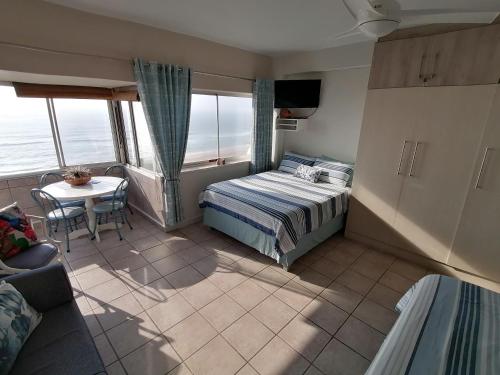 a bedroom with a bed and a table with a couch at Seaview Self Catering Amanzimtoti in Amanzimtoti