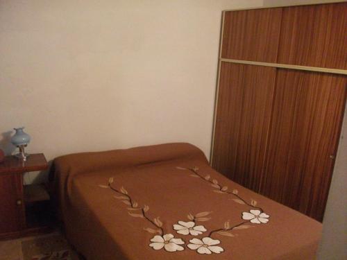 a bed with a brown blanket with flowers on it at San Isidro Cabaña in Mendoza