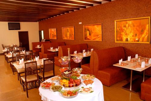 a restaurant with tables and chairs with food on them at Arpanaa Hotel in Tiruvannāmalai