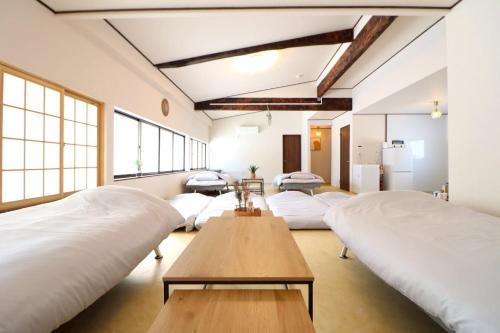 a room with four beds and a table and windows at TOHANA Style ペット宿泊可能 カラオケルーム有り in Hanamaki