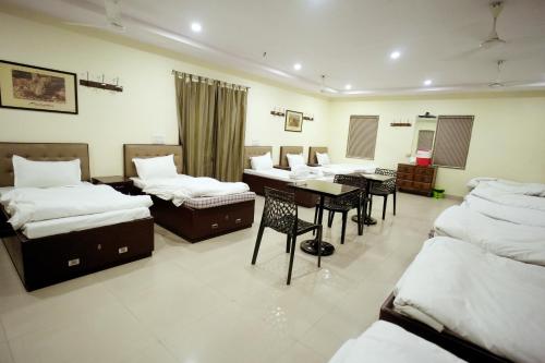 a room with several beds and a table and chairs at Canalta Hotel Restaurant Bar in Jaipur