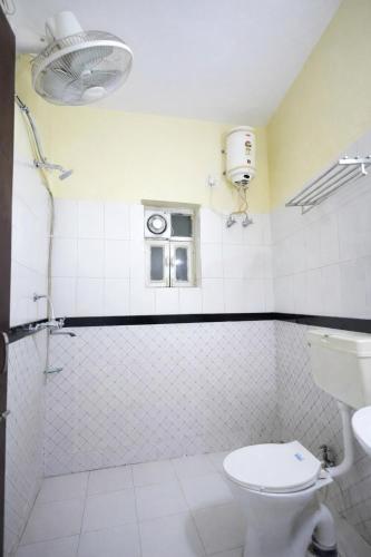 a white bathroom with a toilet and a window at Canalta Hotel Restaurant Bar in Jaipur