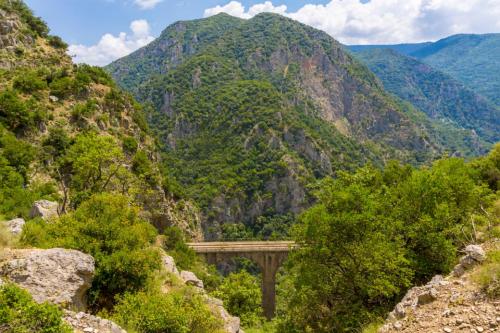 a bridge in the mountains with mountains in the background at Hotel Ena - Elegant Mountain View Stay with Pool in Loutra Ipatis
