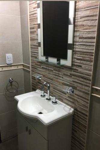 a bathroom with a sink and a tv on the wall at Casa Rossi in Rafaela