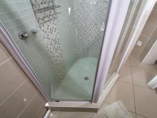 a shower with a glass door in a bathroom at Seaview Apartment Amanzimtoti in Amanzimtoti