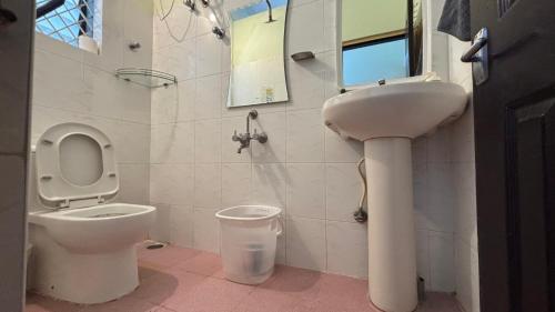 a white bathroom with a toilet and a sink at Aralu in Bangalore