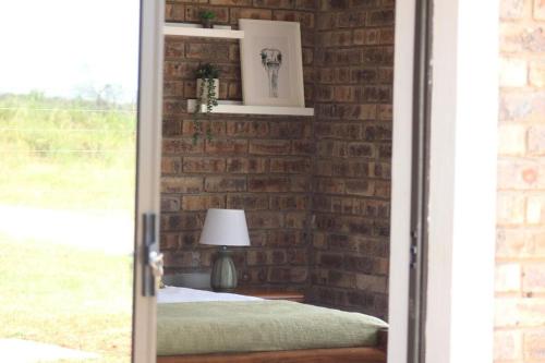 a brick bedroom with a bed and a lamp at Little Amanzi in Pienaarsrivier