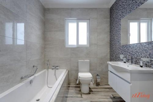 a bathroom with a tub and a toilet and a sink at Pretty Beachfront Penthouse in Mellieha in Mellieħa