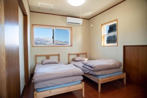 two beds in a room with two windows at 2 minutes from Kugino Station Aso Mountain View, Villa with Heater in Minami Aso