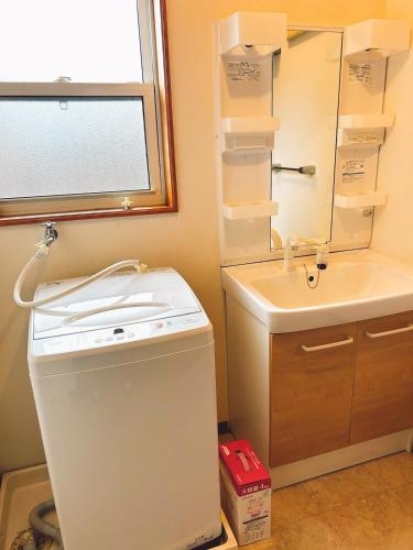 a small bathroom with a sink and a washer at 2 minutes from Kugino Station Aso Mountain View, Villa with Heater in Minami Aso