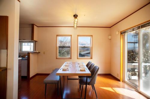 a dining room with a table and chairs and windows at 2 minutes from Kugino Station Aso Mountain View, Villa with Heater in Minami Aso