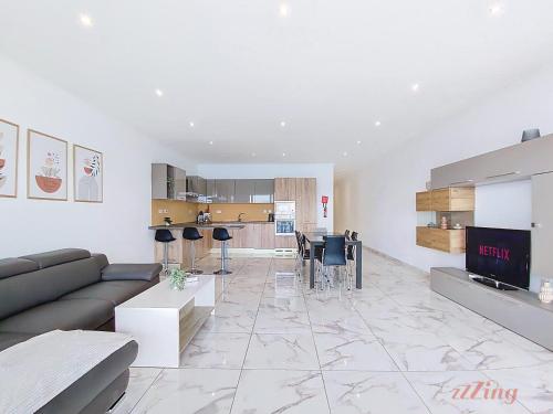 a large living room with a couch and a kitchen at Premium Seafront Apartment with Panoramic Bay Views in Mellieħa