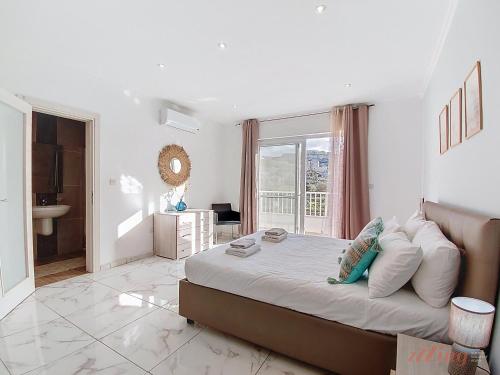 a white bedroom with a large bed and a bathroom at Premium Seafront Apartment with Panoramic Bay Views in Mellieħa