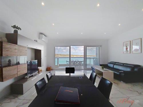 a living room with a table and a couch at Premium Seafront Apartment with Panoramic Bay Views in Mellieħa
