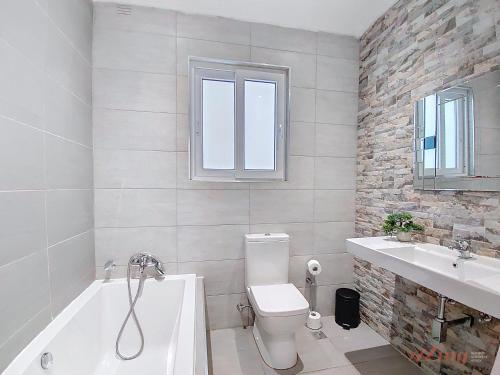 a bathroom with a tub and a toilet and a sink at Premium Seafront Apartment with Panoramic Bay Views in Mellieħa