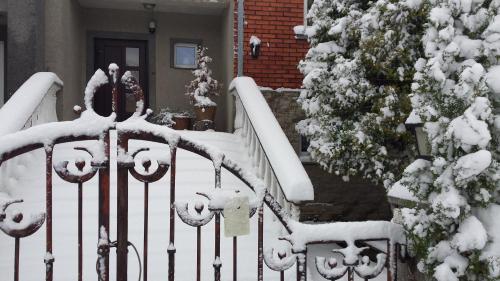 a fence covered in snow in front of a house at Home for Guests Lakštingala in Šiauliai