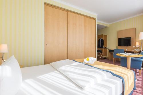 a hotel room with a bed and a tv at Strand-Hotel Hübner in Warnemünde