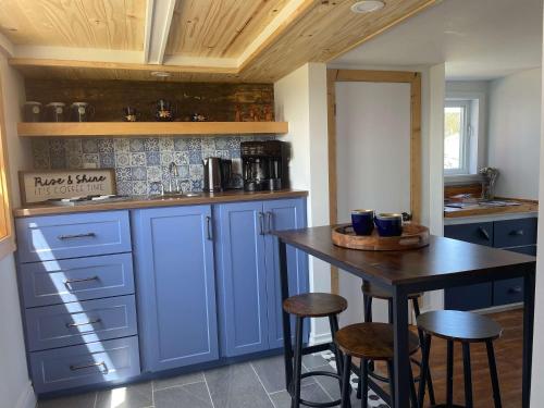 a kitchen with blue cabinets and a table with stools at The Moose Twillingate Island in Twillingate