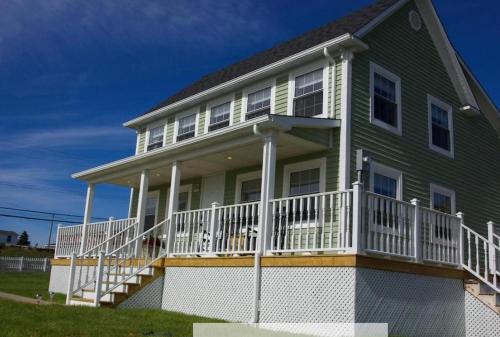 ein großes grünes Haus mit einer weißen Veranda in der Unterkunft Skipper Tom's in Twillingate