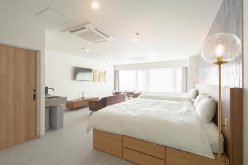 a bedroom with a white bed and a bathroom at くらしホテル Hakodate in Hakodate
