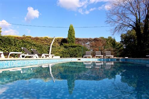 a swimming pool with a bunch of chairs around it at Hotel Les Oliviers in Draguignan