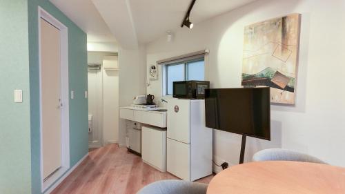 a small kitchen with a refrigerator and a table at 9STAY Shibuya Shinsen in Tokyo