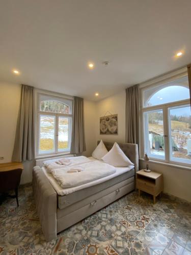 ein Schlafzimmer mit einem großen Bett und zwei Fenstern in der Unterkunft frankys cafe in Bärenstein