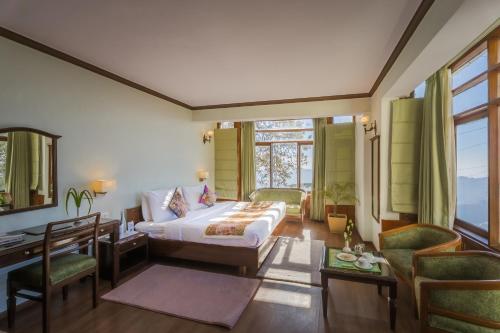 a bedroom with a bed and a desk and chairs at Tripli Hotels Le Royale, Shimla in Shimla