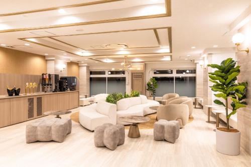 a lobby with white couches and tables at Ooedo Onsen Monogatari Premium Shima Saichoraku in Shima