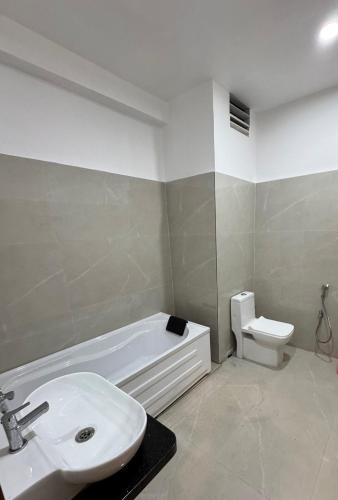 a bathroom with a sink and a tub and a toilet at Hotel M Plaza New Digha in Digha