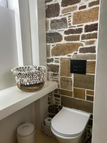 a bathroom with a white toilet and a brick wall at Petrino Minimal in Dhéndra