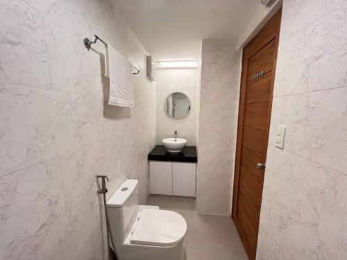 a white bathroom with a toilet and a sink at Casa Aya Suites in Puerto Galera