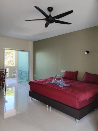 a bedroom with a red bed with a ceiling fan at Spy Home apartment in Khao Lak