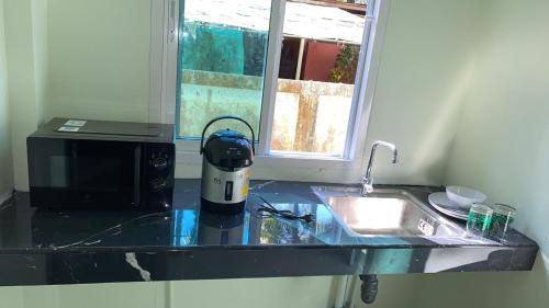 a kitchen counter with a microwave and a sink at Spy Home apartment in Khao Lak