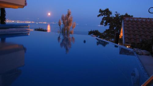 a swimming pool with a view of the ocean at night at Apartments Villa Krasa in Lovran