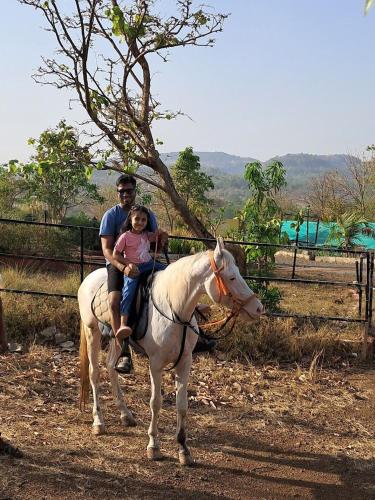 a man and a child riding a white horse at Gaudham Periyar Farms in Jambhulpāda