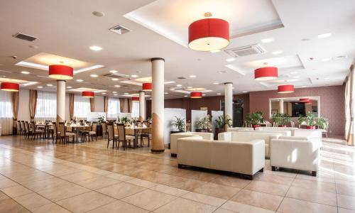 a restaurant with white tables and chairs and red lights at Hotel Austeria Conference & Spa in Ciechocinek