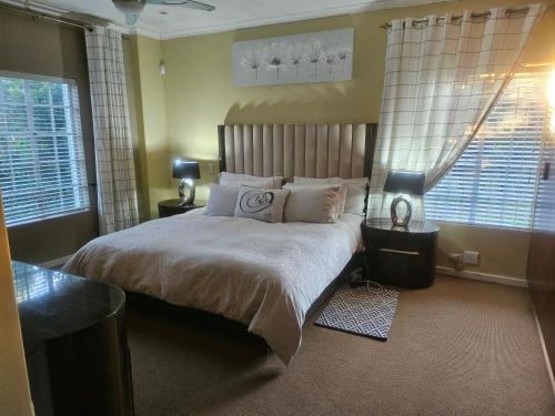 a bedroom with a large bed and two windows at 20 in Crescent in Gqeberha