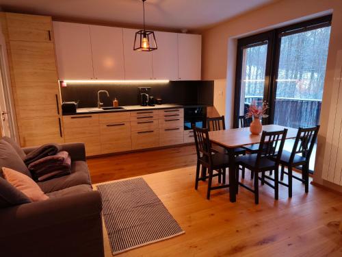 a kitchen and dining room with a table and chairs at Apartmán Nest Brčálník in Železná Ruda