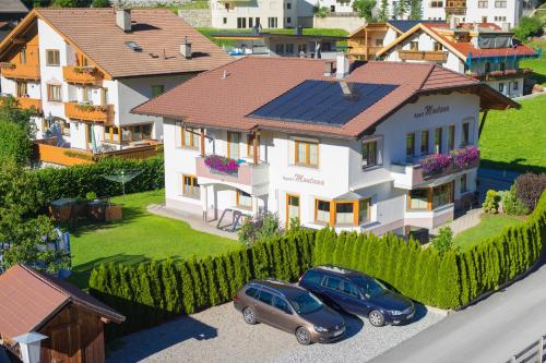 two cars parked in front of a house with solar panels at Apart Montana in Nauders