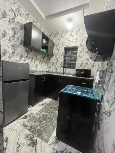 a kitchen with black cabinets and a black refrigerator at 6c Apartment in Port Harcourt