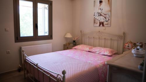 a bedroom with a bed with pink sheets and a window at Η Αυλή της Μαρίας in Áyios Thomás