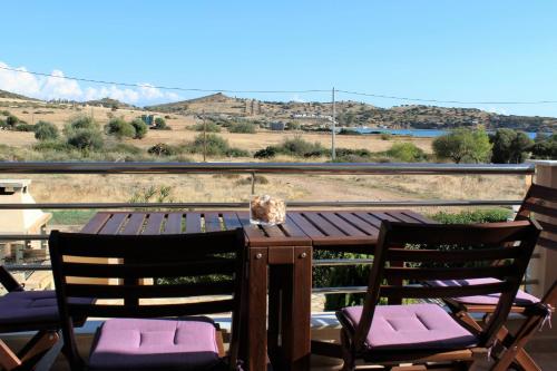 a wooden table with chairs and a view of the mountains at Helen's Sounio Apartments in Sounio