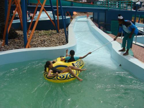 a man pulling a child on a raft on a water slide at Vista Bonita Apartments in Mossel Bay