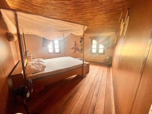 sypialnia z łóżkiem z baldachimem i drewnianą podłogą w obiekcie Case beach w mieście Ngalou Sessène
