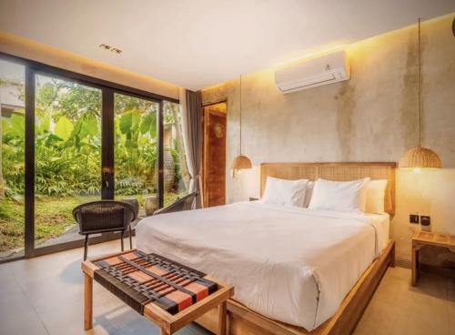 a bedroom with a bed and a large window at Pigstone Design Studios Beachfront in Tanah Lot