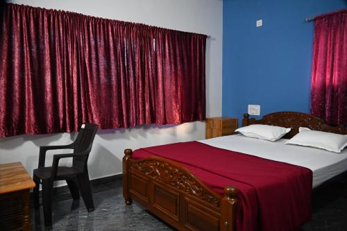 a bedroom with a bed and a chair and red curtains at Ramleela Stay, Gokarna in Ankola